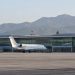 Passenger jet parked on the apron outside a modern airport terminal with a long glass facade in Burbank in soft early-morning daylight.