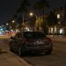Quiet West Hollywood street corner at night under street lamps, a lone parked sedan at the curb beside palm trees and low-rise buildings.