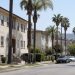 Residential street of older stucco apartment buildings and palm trees on the Westside of Los Angeles in afternoon daylight, seen through a long lens.
