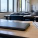 Rows of closed student laptops on desks in an empty Southern California classroom in afternoon daylight, illustrating the student data breach.