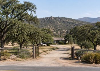 Rural Valley Center property with a dirt driveway, live oaks and dry chaparral hills in neutral daylight, illustrating a San Diego County murder case.