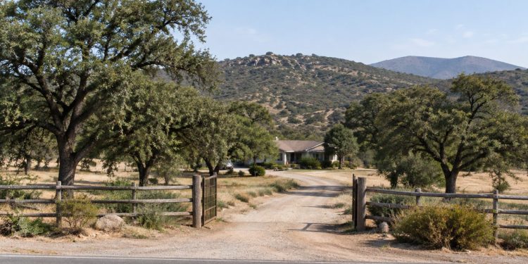 Rural Valley Center property with a dirt driveway, live oaks and dry chaparral hills in neutral daylight, illustrating a San Diego County murder case.