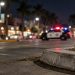 Santa Monica Boulevard in West Hollywood at night, with a curb in sharp focus and a patrol SUV blurred in the background under street lamps.