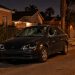 Sedan with a shattered windshield, broken headlights and smashed driver's-side window parked on a narrow South Los Angeles residential street at night.