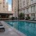 Small rectangular courtyard pool with lounge chairs between tall masonry walls of an older downtown Los Angeles hotel in neutral daylight.