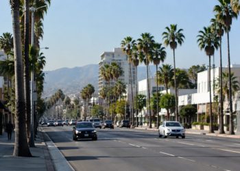 Wide daylight view of Santa Monica Boulevard in West Hollywood, with palm trees and low-rise commercial buildings along the busy corridor.