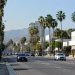Wide daylight view of Santa Monica Boulevard in West Hollywood, with palm trees and low-rise commercial buildings along the busy corridor.