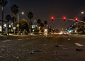 Wide multi-lane boulevard intersection in Manhattan Beach at night under street lamps, with broken glass and plastic fragments scattered across the asphalt.
