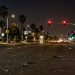 Wide multi-lane boulevard intersection in Manhattan Beach at night under street lamps, with broken glass and plastic fragments scattered across the asphalt.