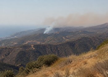 Wide view of dry chaparral ridgelines in the Santa Monica Mountains near Malibu with a thin plume of smoke rising over the hills in afternoon daylight.
